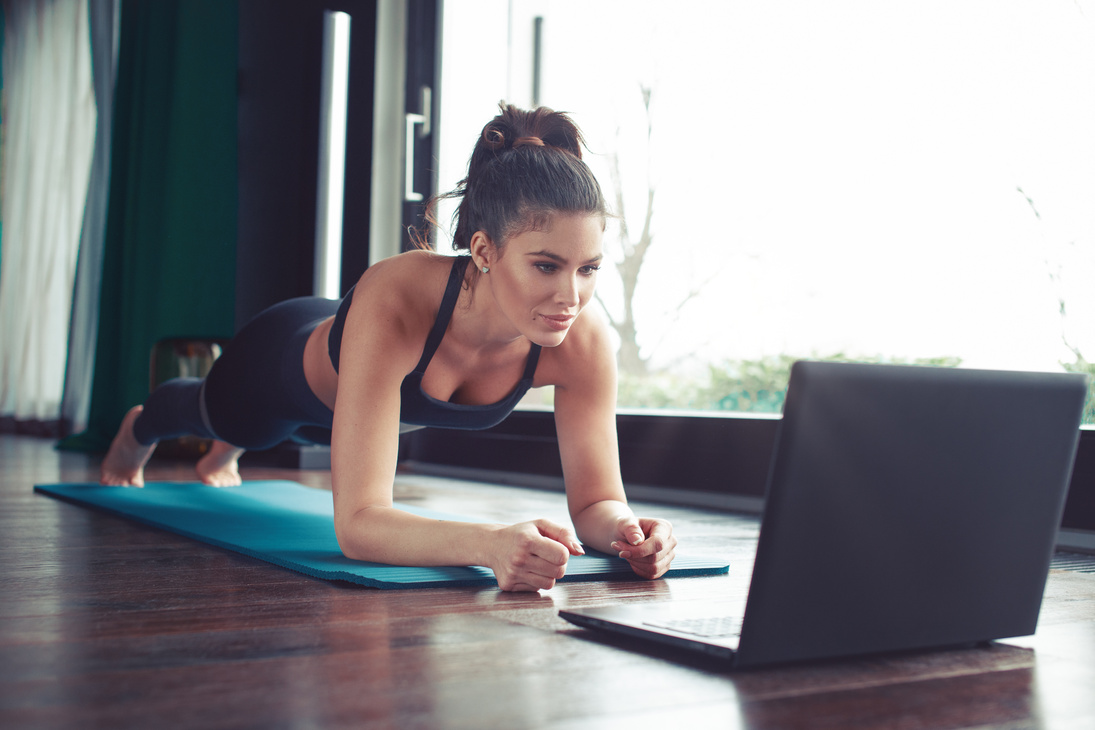 Young fitness trainer showing plank exercise online